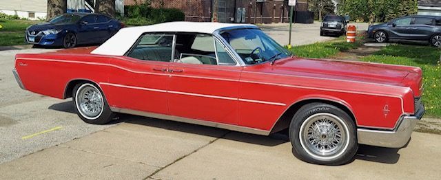 Red classic convertible car parked on a driveway in a residential area