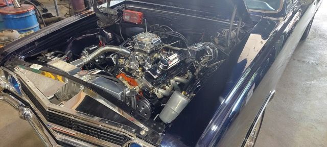 Classic car engine bay with a polished V8 in a dark blue car, viewed from the front.