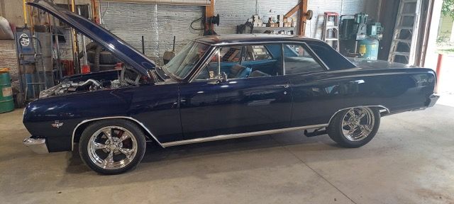 Dark blue classic car with hood open in a garage
