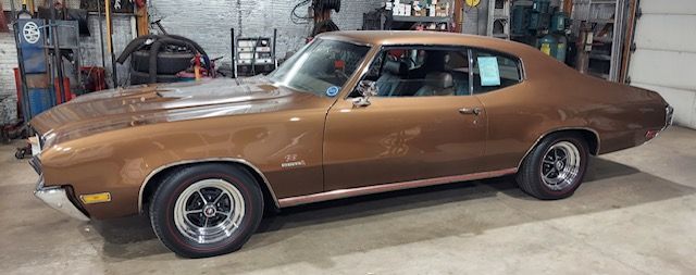 Bronze classic muscle car parked in a workshop garage, side view
