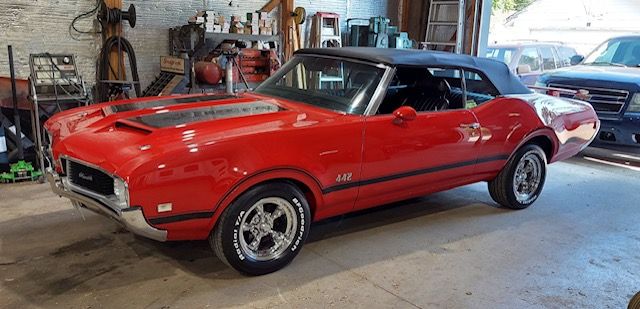 Red classic convertible sports car parked inside a garage or workshop.
