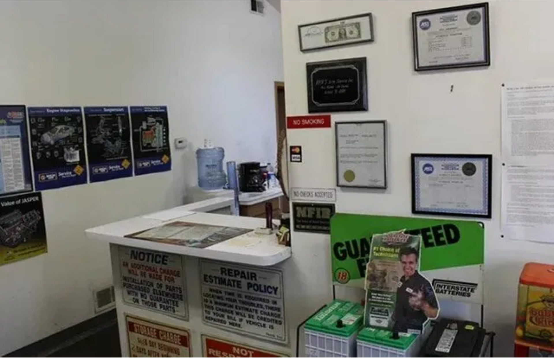 Office lobby with bulletin boards, framed certificates, and a green “Guns Feed” display stand