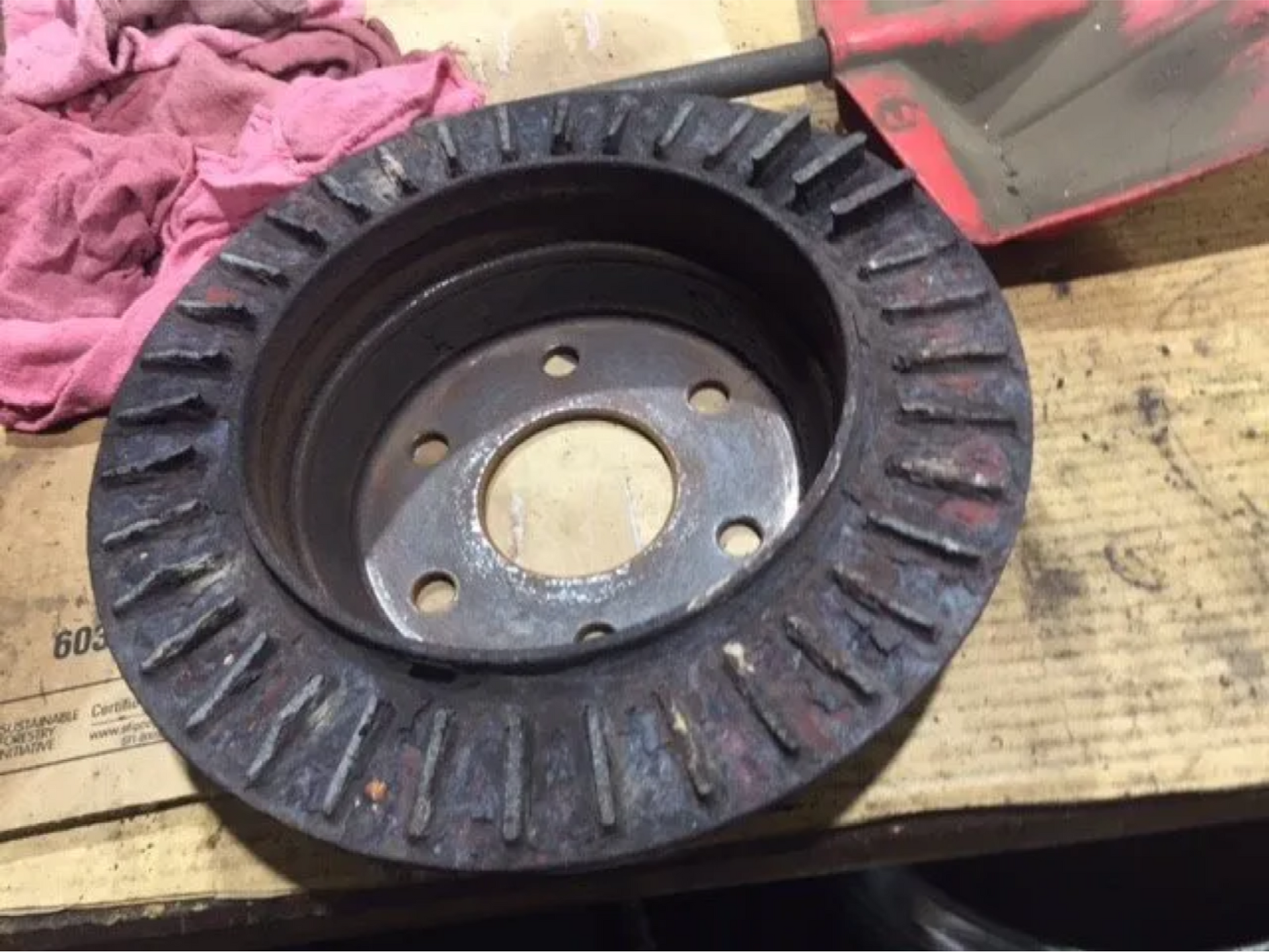 Black rubber tire-like wheel hub with a metal center resting on a wooden pallet.