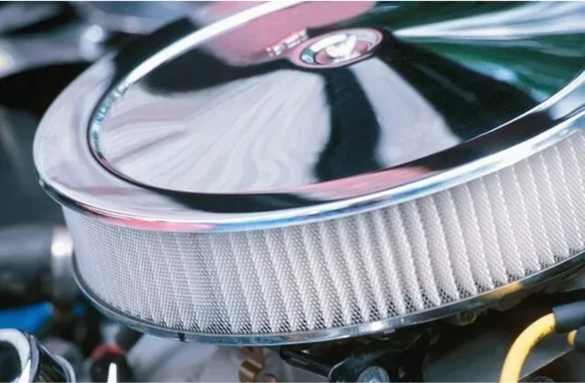 Close-up of a chrome air filter on a car engine, with black and yellow components visible underneath