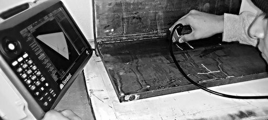 A technician uses an ultrasonic testing device to inspect a metal surface for internal flaws.