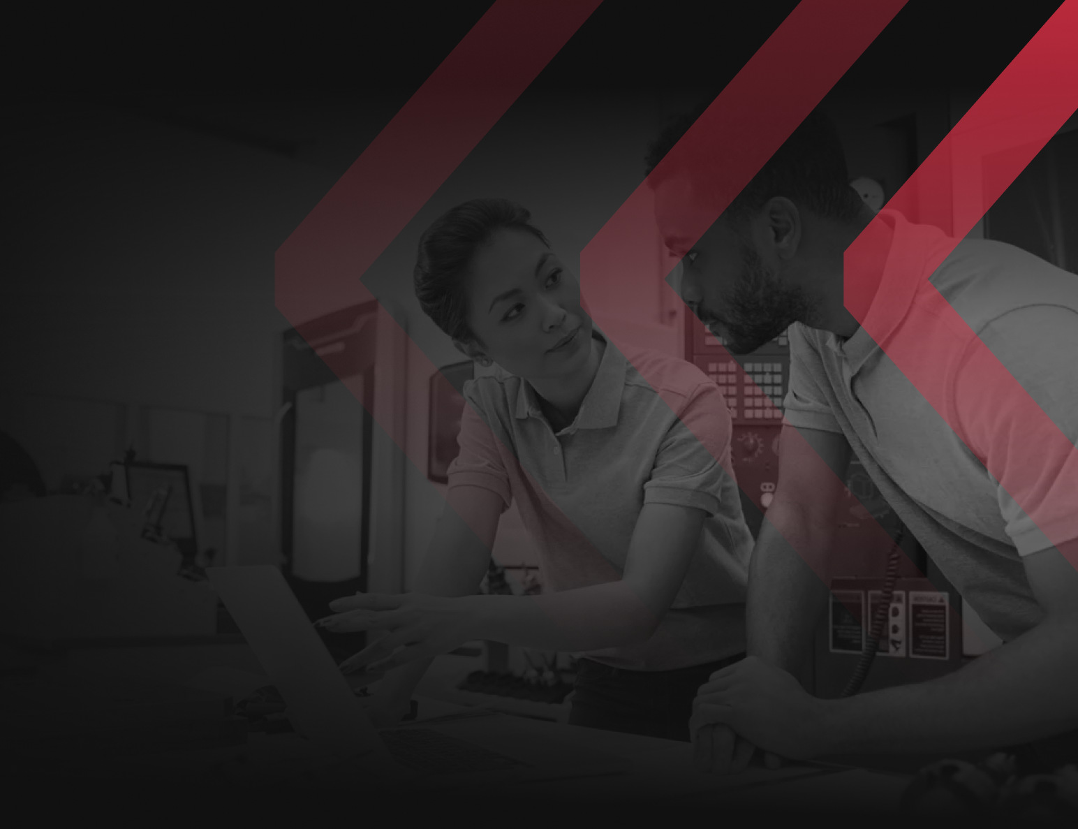 Two colleagues in a workspace looking at a laptop screen, overlaid with stylized red chevron patterns.
