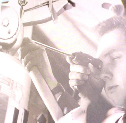 A person focuses intently while using a small hand-held tool to work on the mechanical components of a device.
