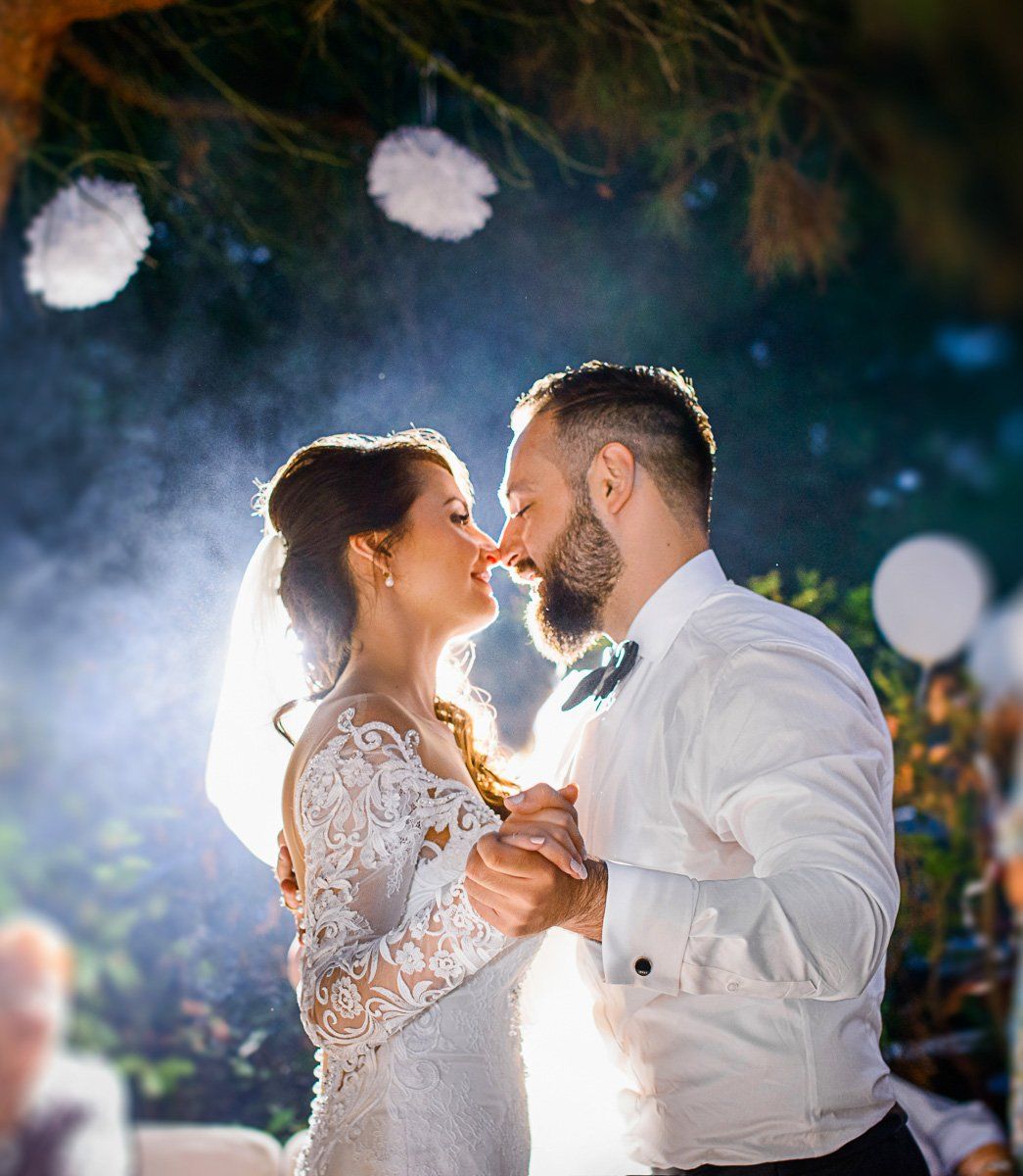 A couple almost kiss during their first dance with string lights provided by DJ Aaron Bracken.