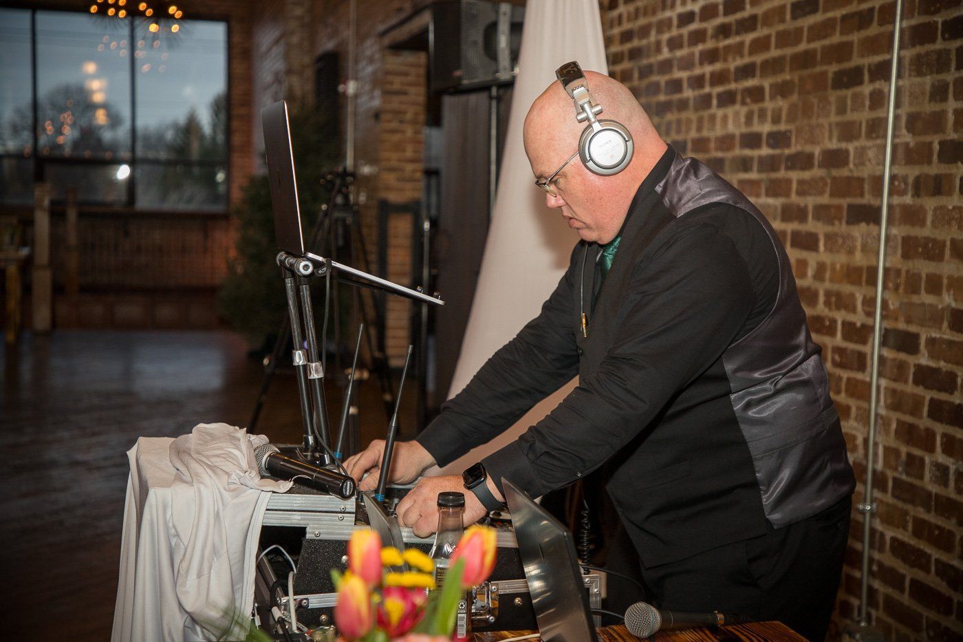 Wedding DJ Aaron with 30 years of keeping dance floors full adjusts the volume on the sound board.