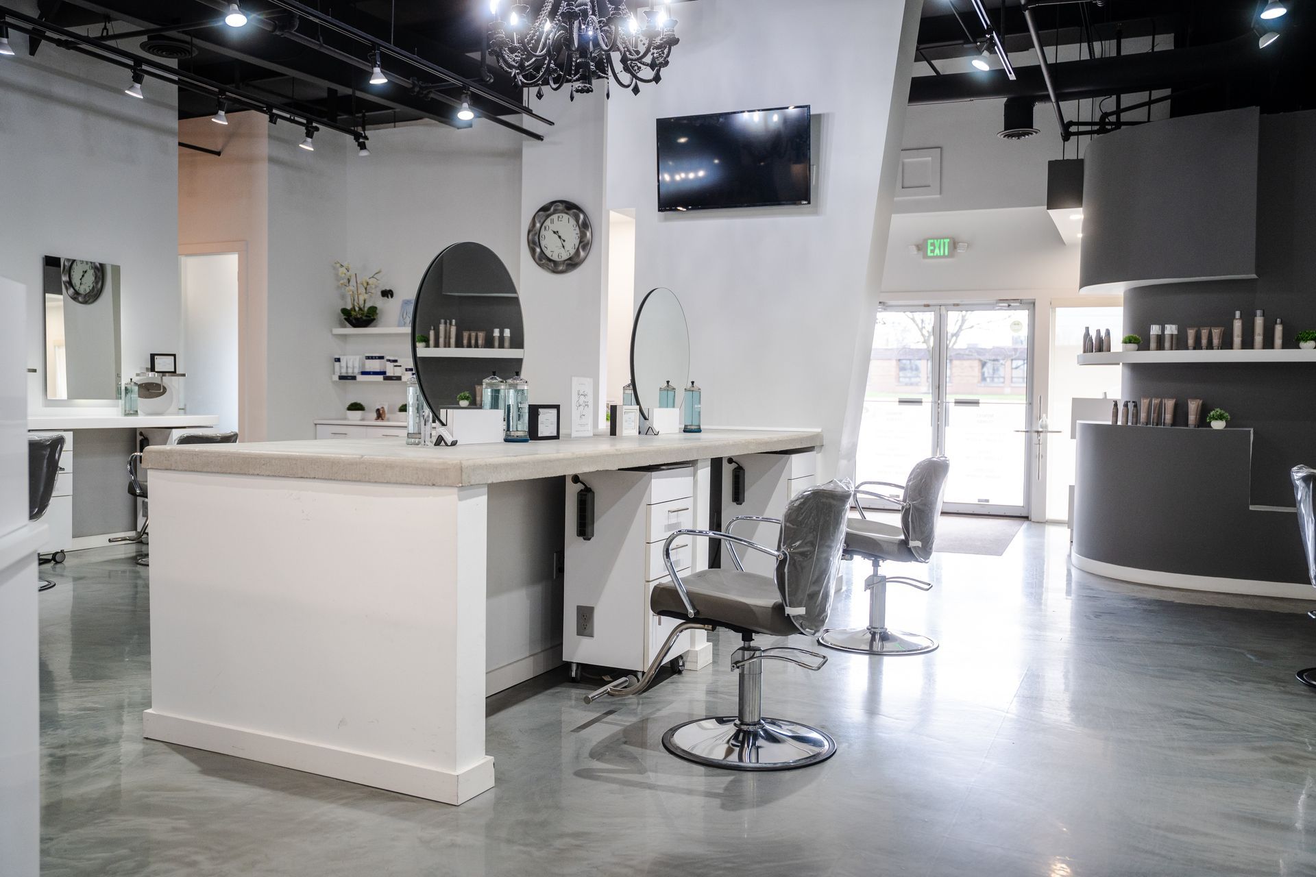 Hair salon interior with styling stations, products, and a television.