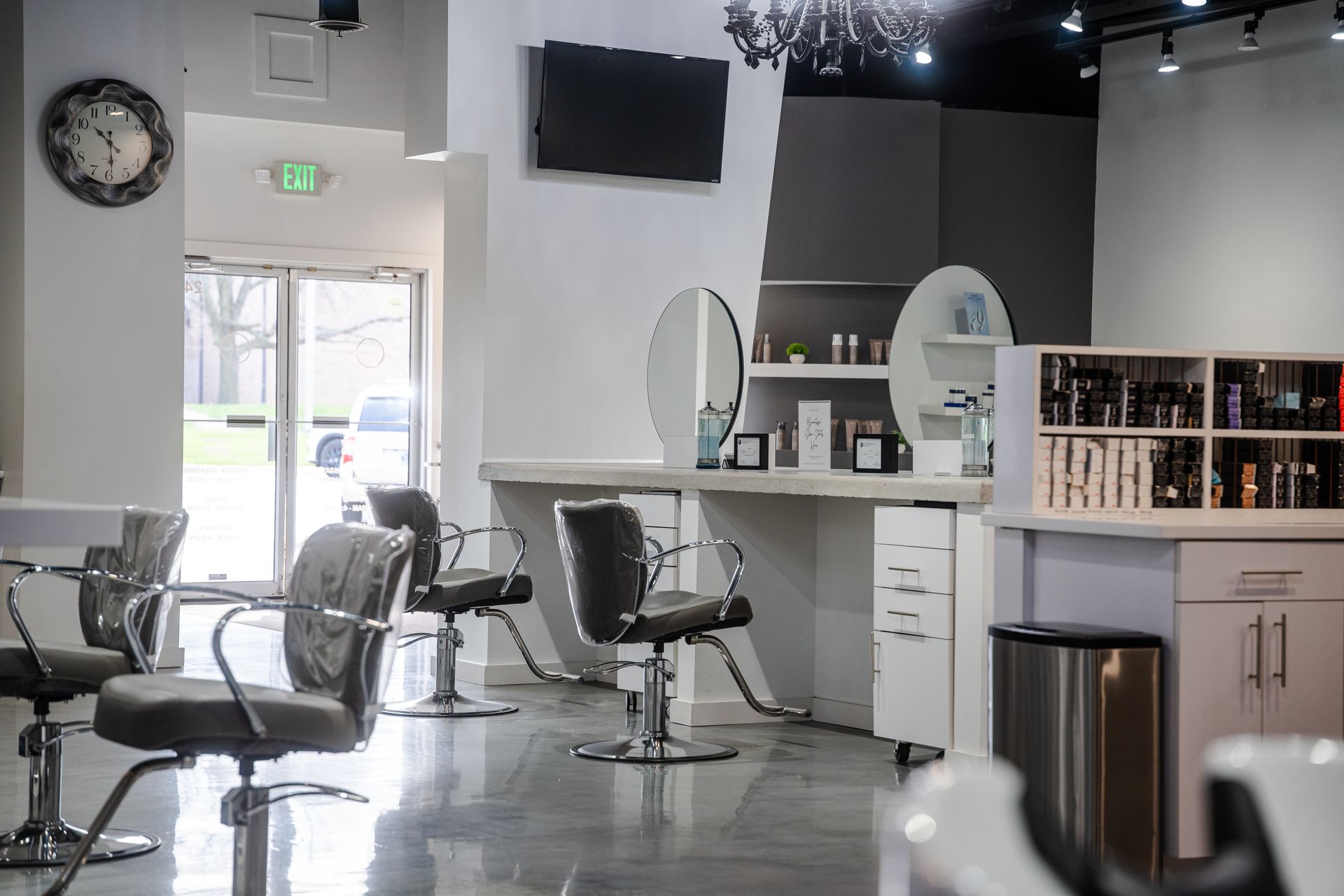 Hair salon interior with gray chairs, mirrors, and product shelves.