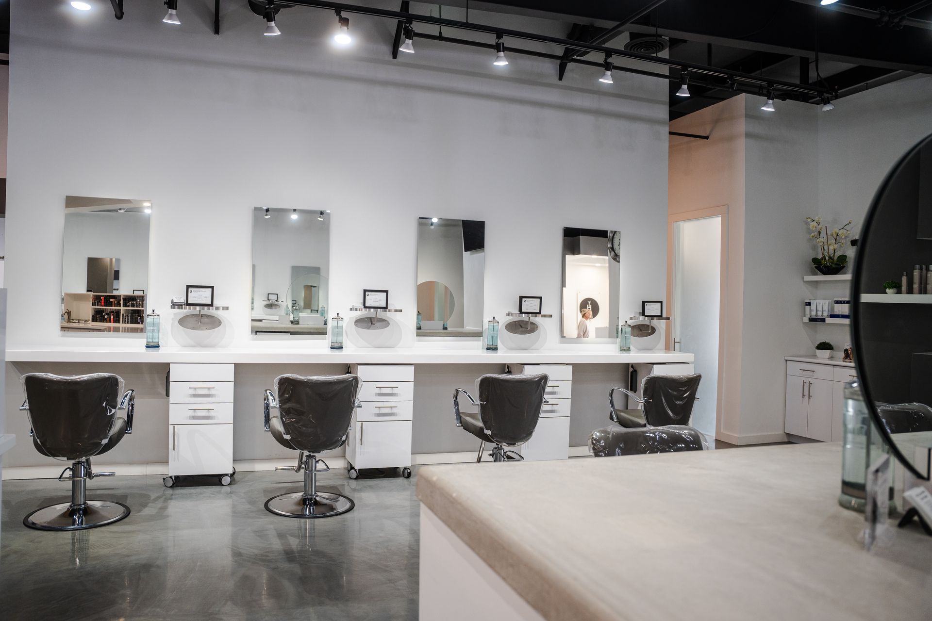 Interior of a modern hair salon with stations, mirrors, and black chairs.