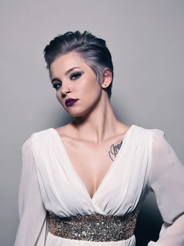 Woman with short, gray hair, wearing a white dress and dark lipstick.