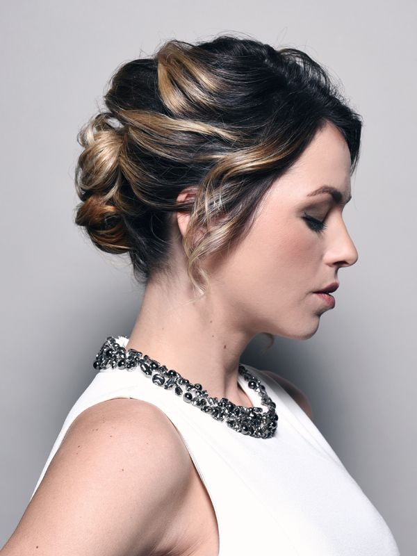 Woman in white dress with updo hairstyle and jeweled collar.