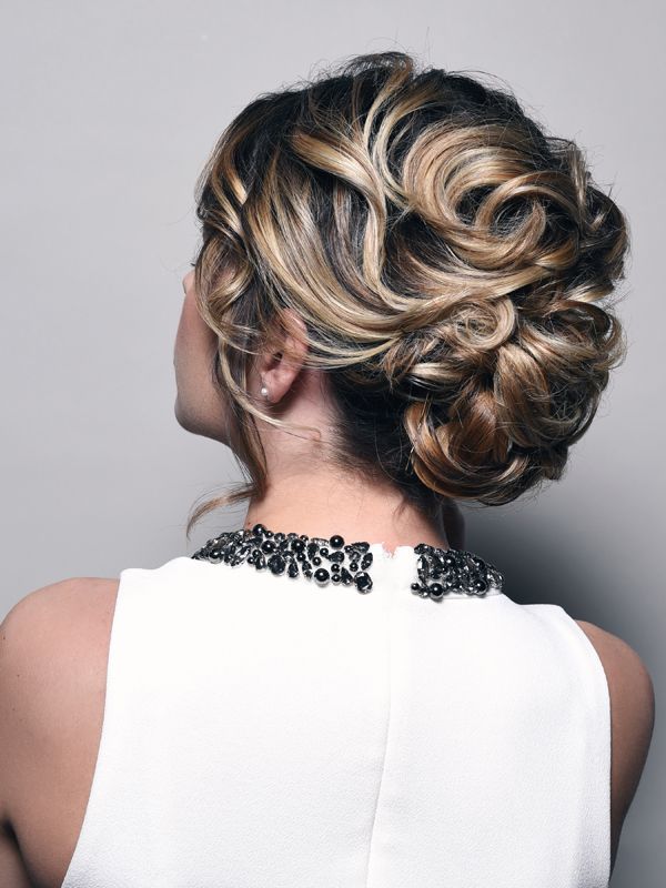 Woman with blonde and brown curly updo hairstyle, wearing a white dress.