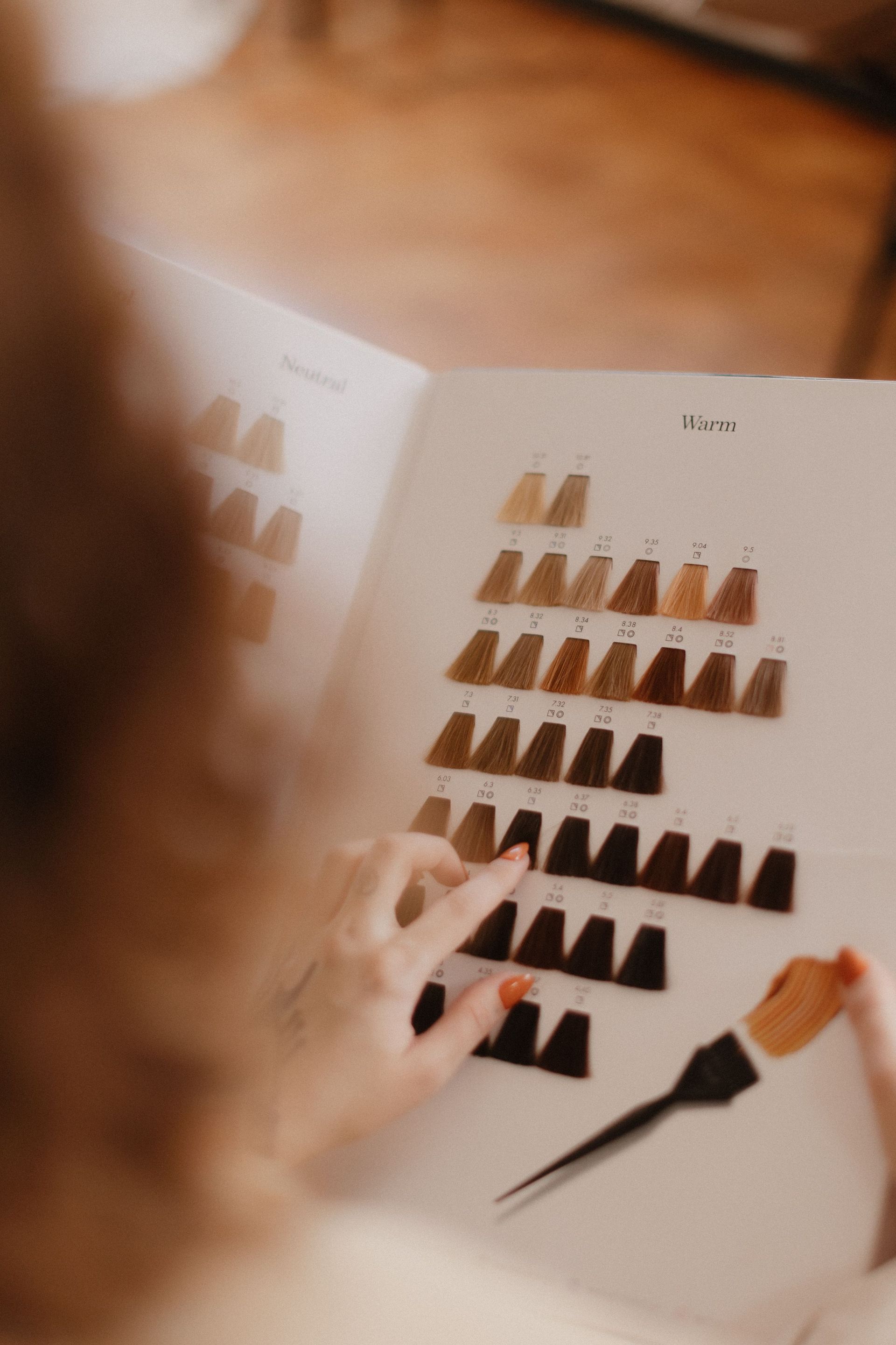 Hand selecting dark color swatches on a white color palette sheet
