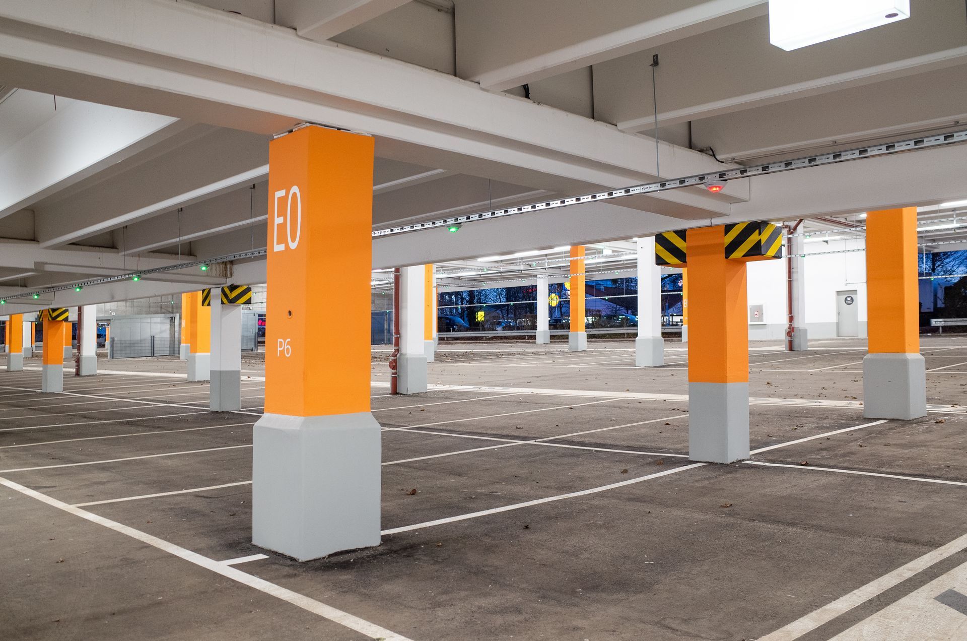 Empty underground parking garage with orange-and-gray support columns and painted parking spaces