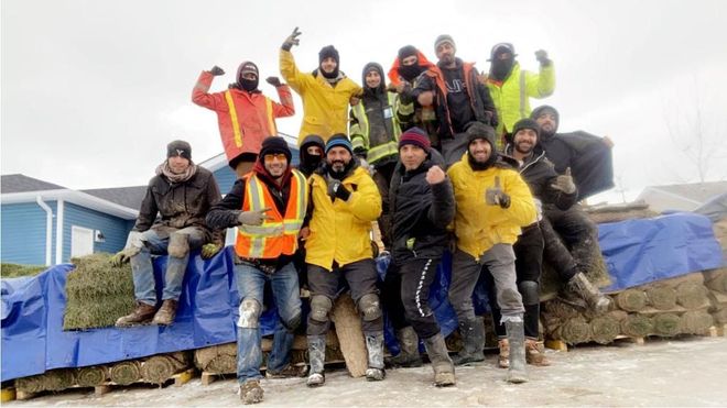 Group of professionals in colorful jackets posing with backpacks on a snowy mountain trail