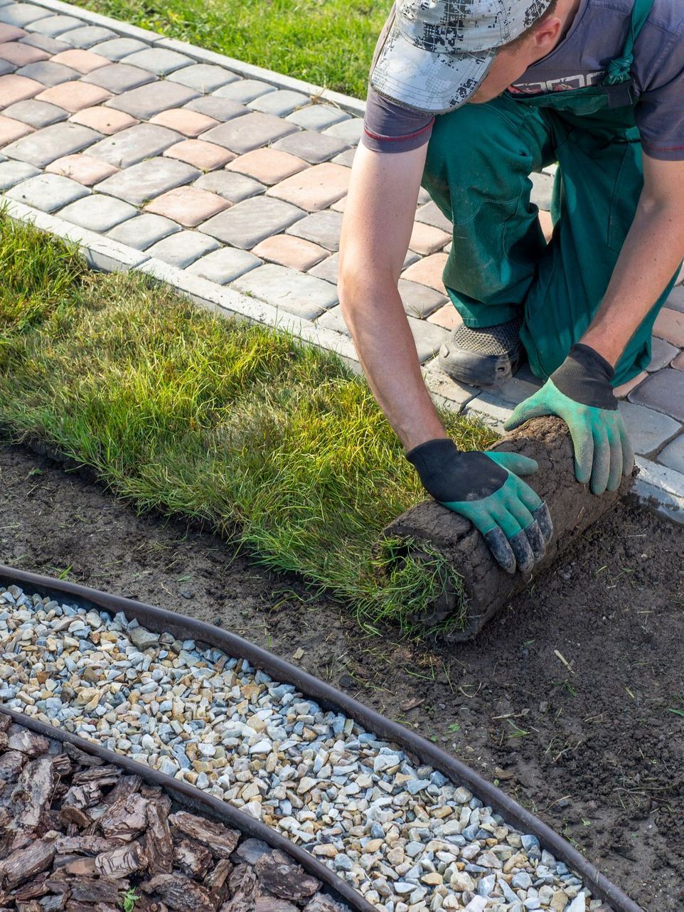 A man is laying a roll of grass in a garden.