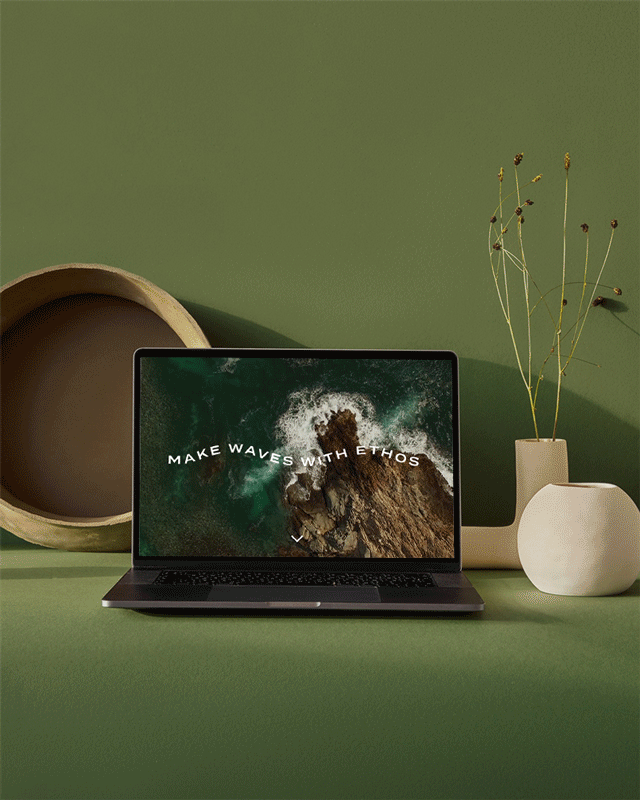 Laptop on a green surface displaying an ocean with 