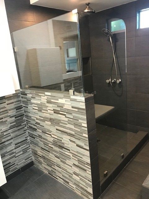 A bathroom with a walk in shower with a glass door.