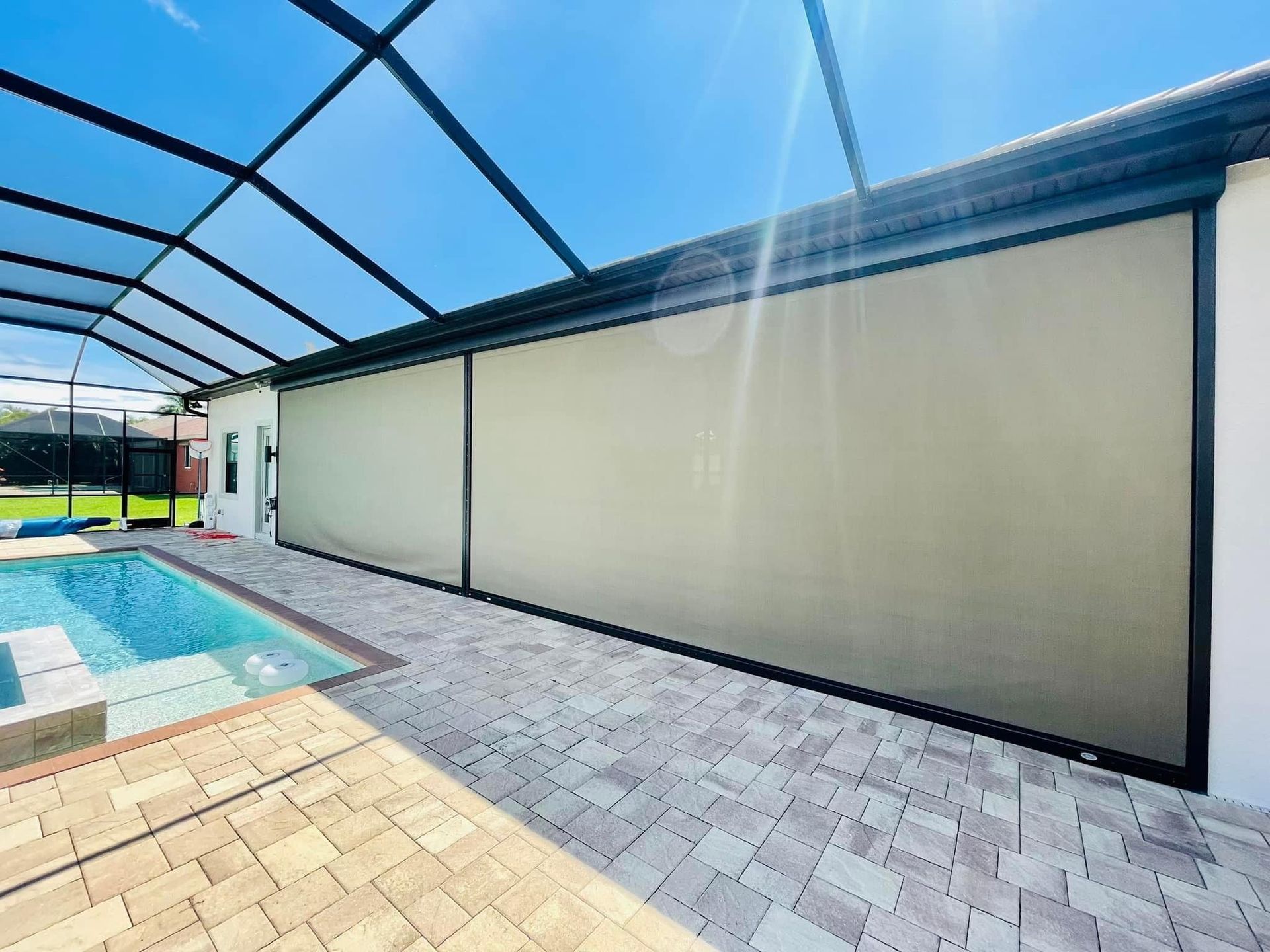 Poolside patio with screened enclosure, beige wall, and bright sunlight