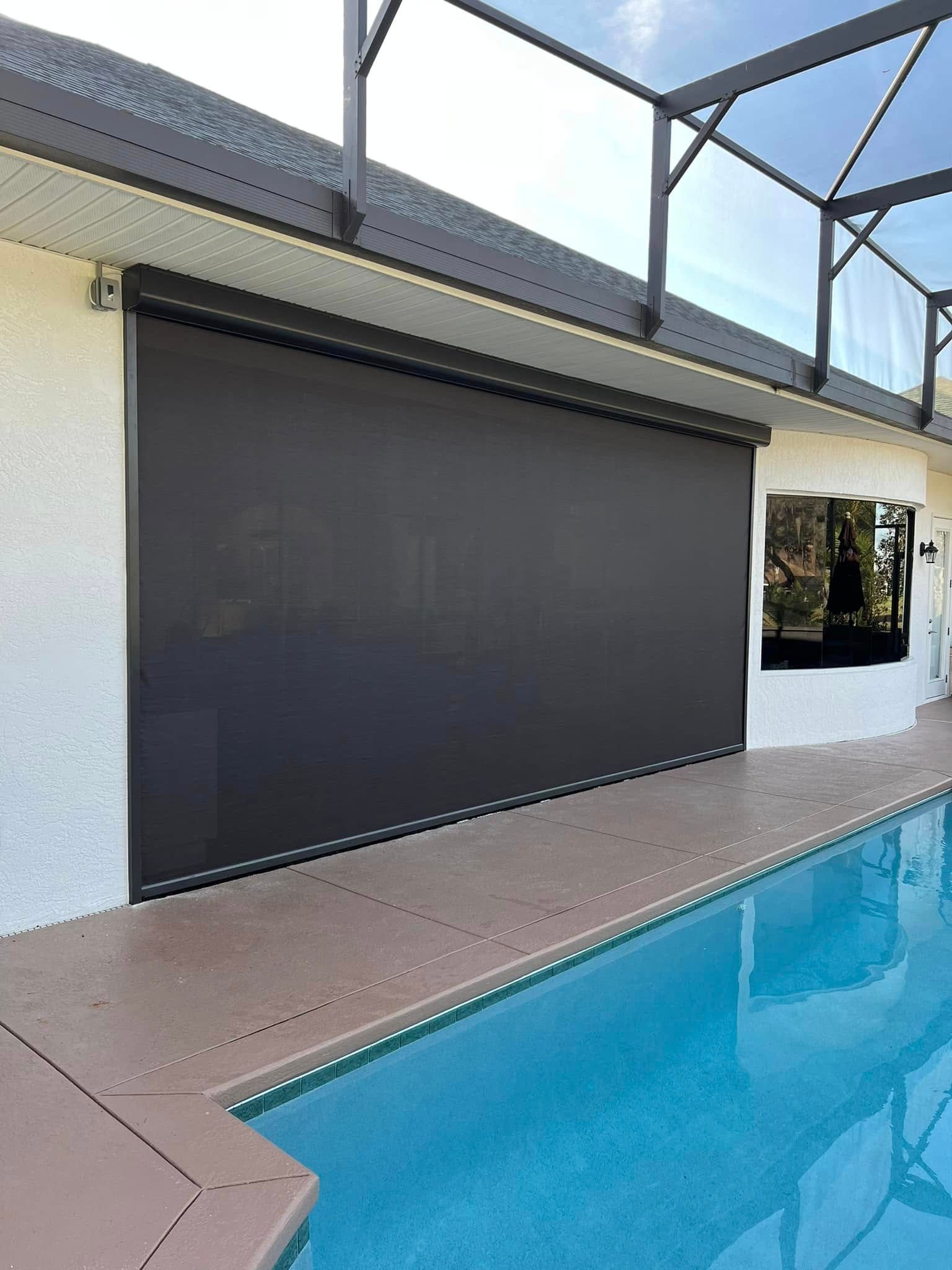 Poolside patio with a large black retractable screen and blue swimming pool.