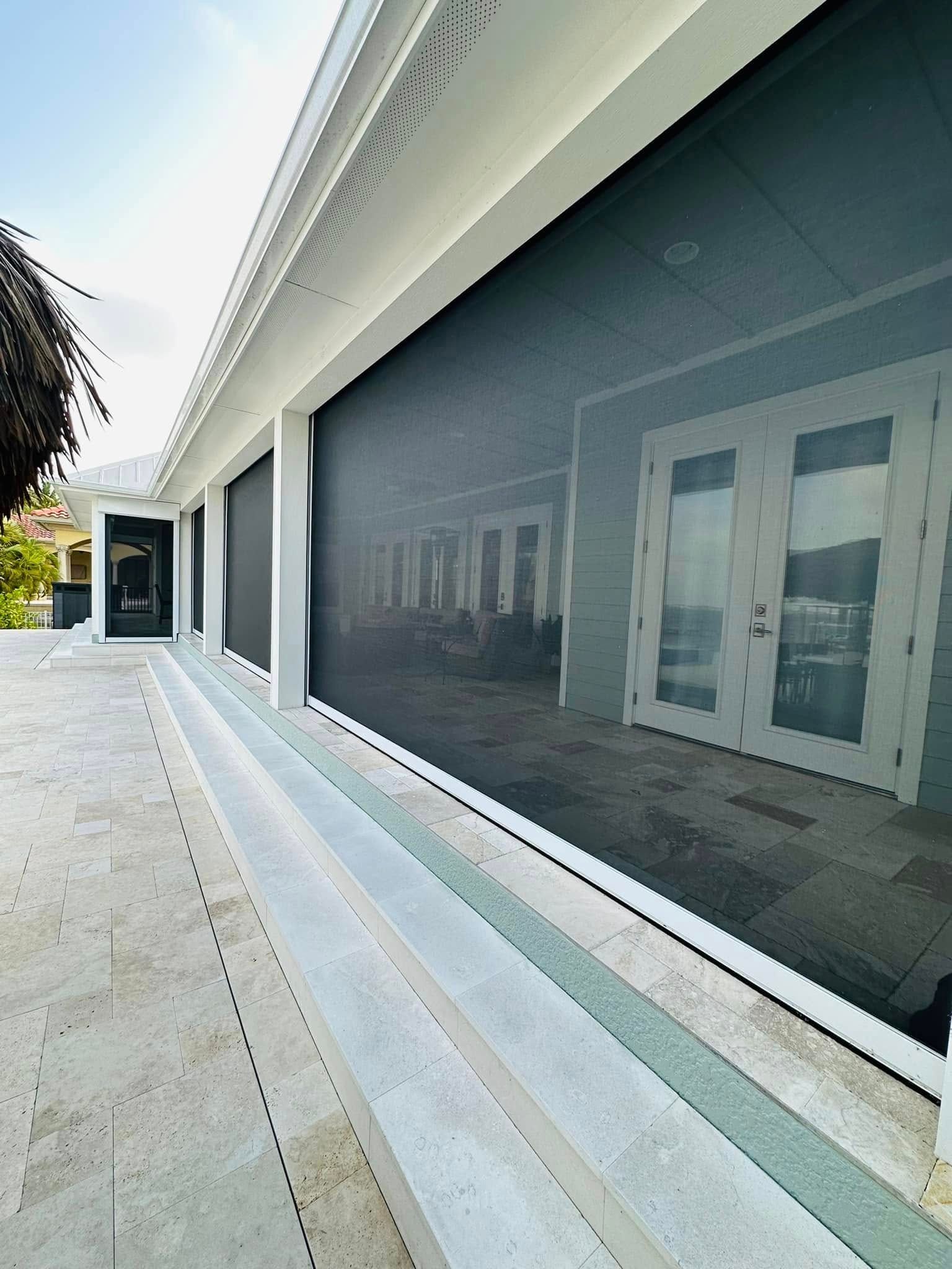 Modern building exterior with large tinted windows and a long tiled walkway