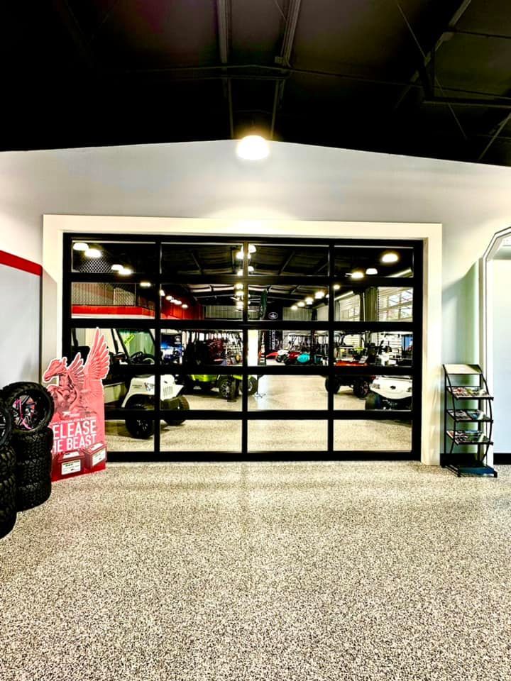 Gym interior with black-framed glass wall, bright lights, and speckled floor