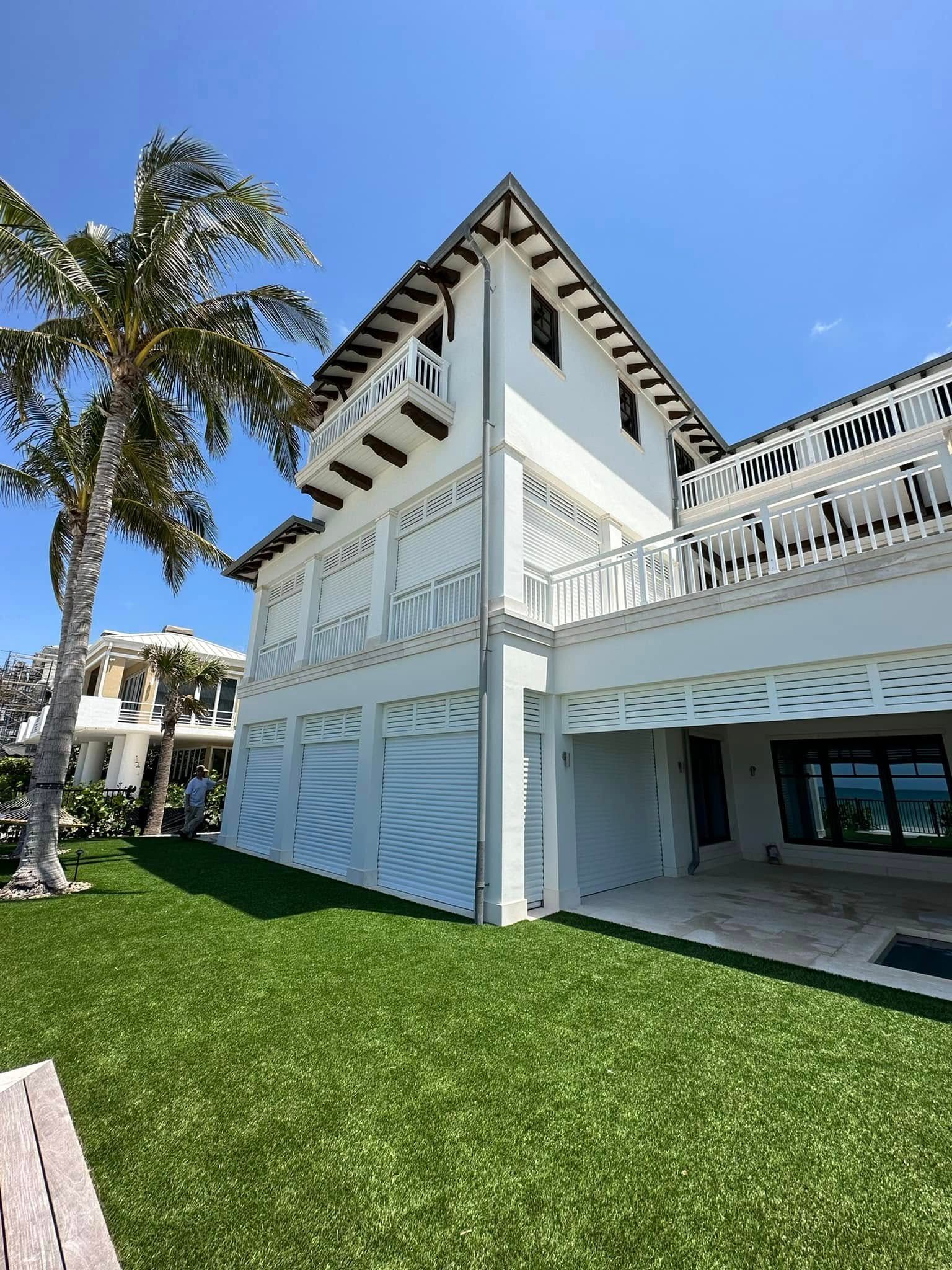 White coastal building with palm tree, green lawn, and blue sky