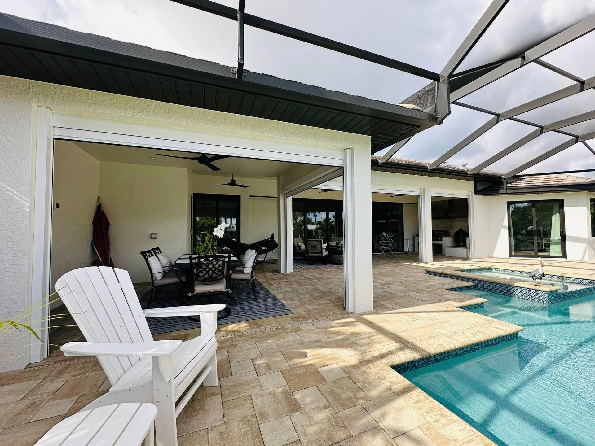 Patio with white chair, covered seating area, and turquoise swimming pool under a screened lanai