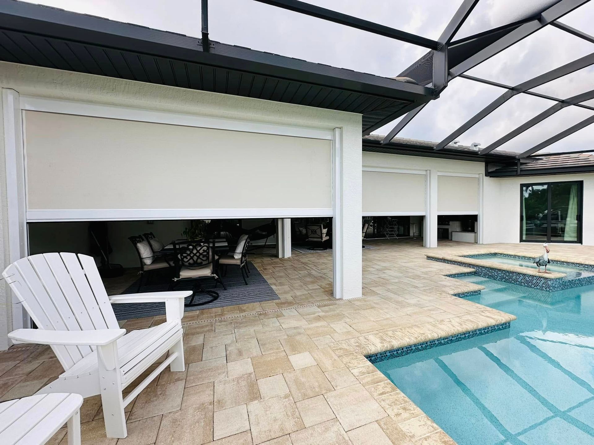 Covered patio with white chair beside a swimming pool and lounge area