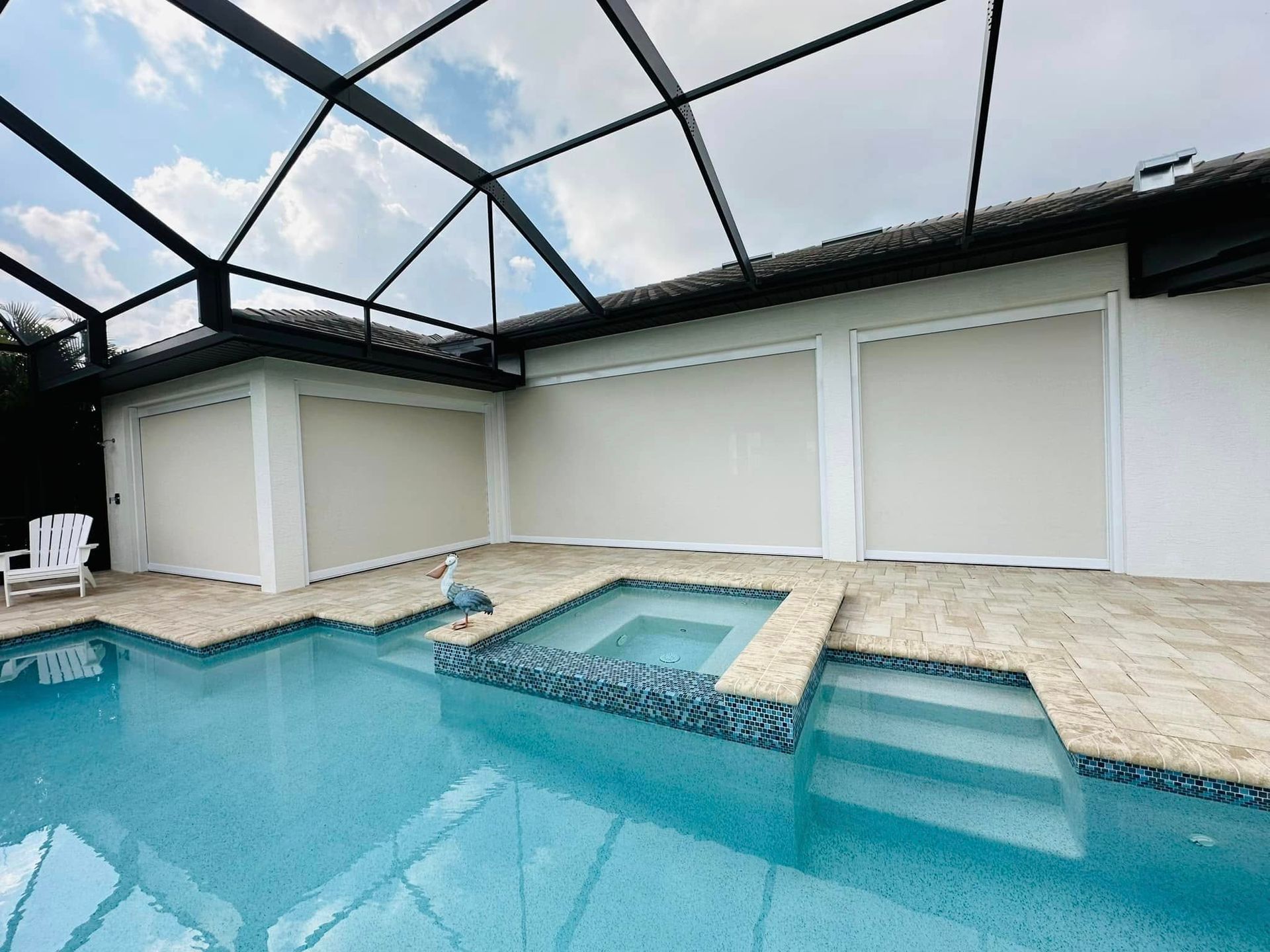 Indoor pool with a screened enclosure, blue water, and white lounge chairs by the deck