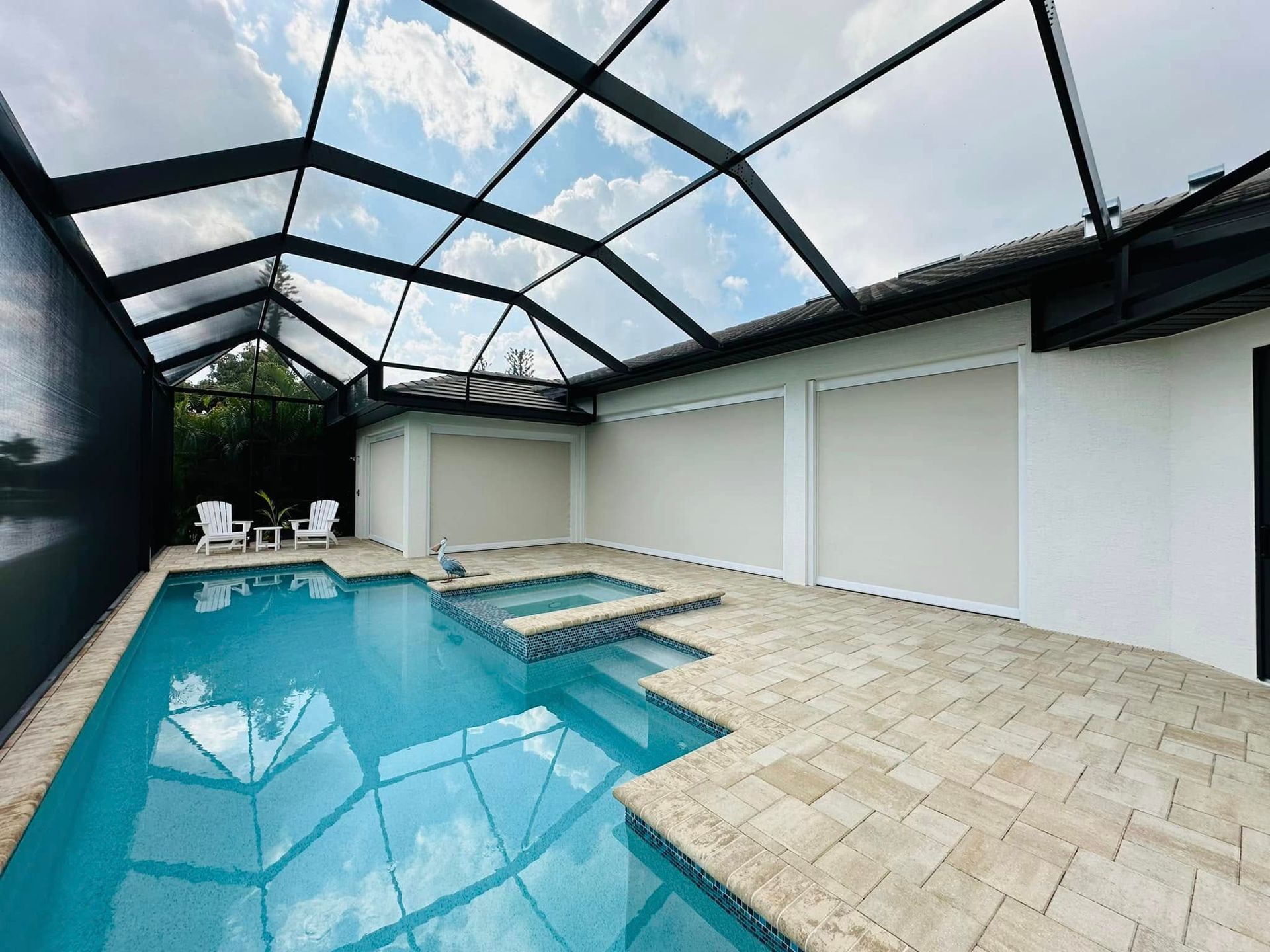 Indoor pool under a glass roof with blue water and beige tile decking