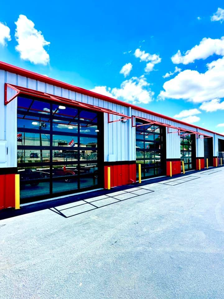 Modern industrial building with red trim, large glass windows, and a bright blue sky