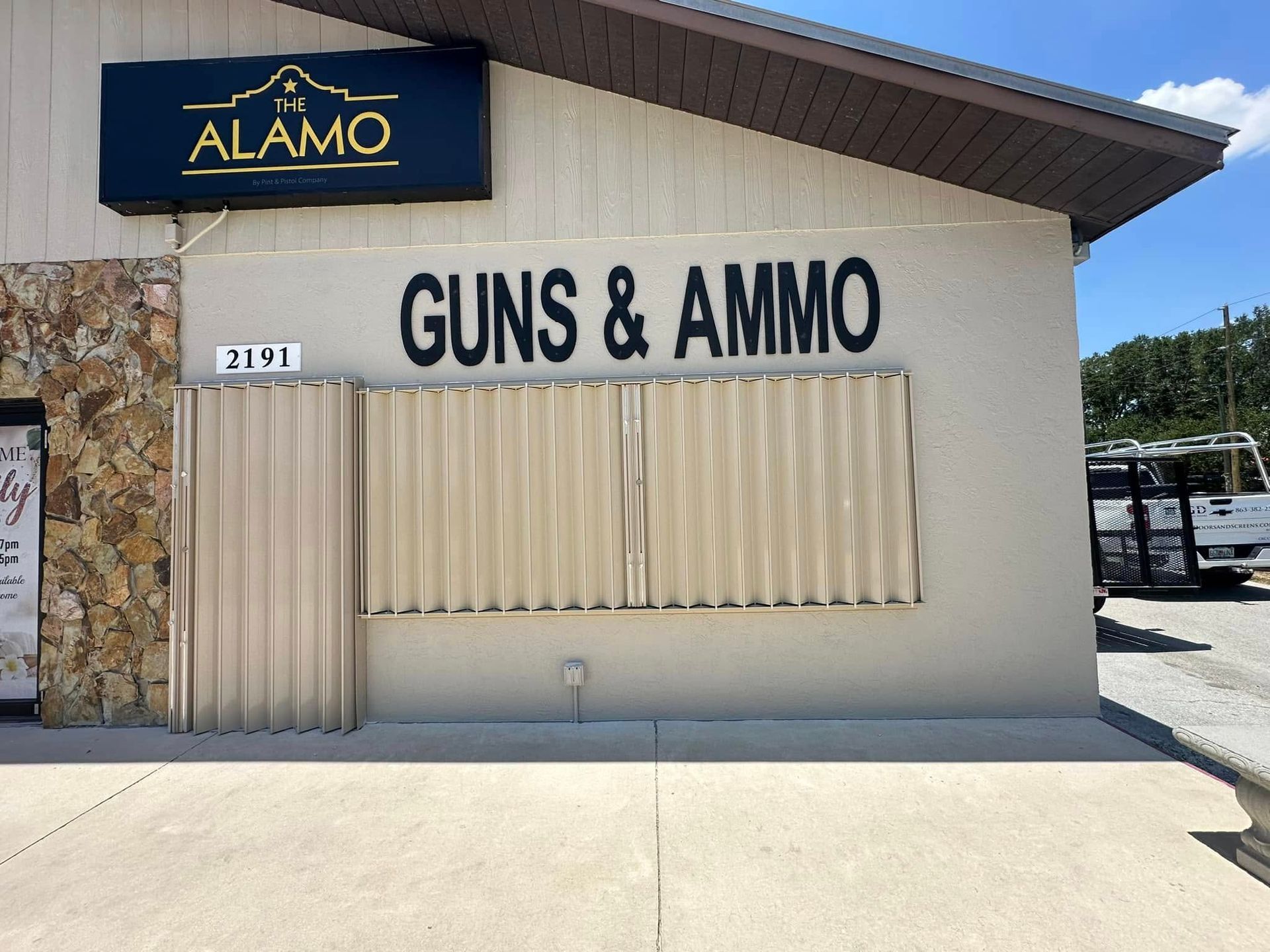 Storefront with ALAMO sign and “GUNS & AMMO” lettering on a beige building