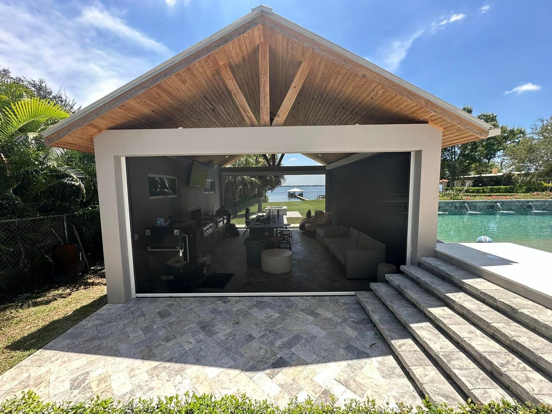 Open-sided poolside pavilion with a thatched roof, steps, and ocean view beyond.