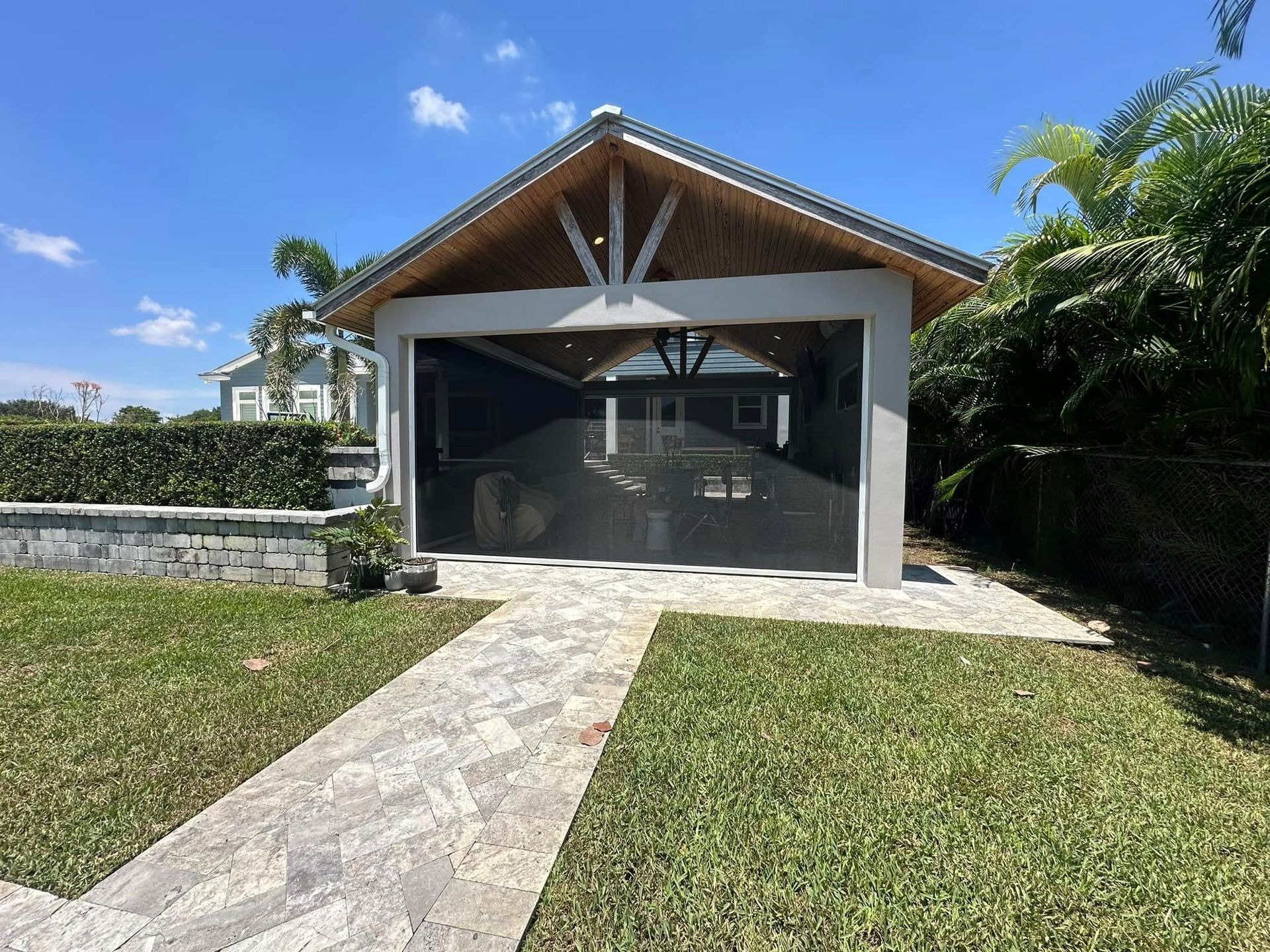 Modern house with open garage and stone driveway, surrounded by tropical greenery
