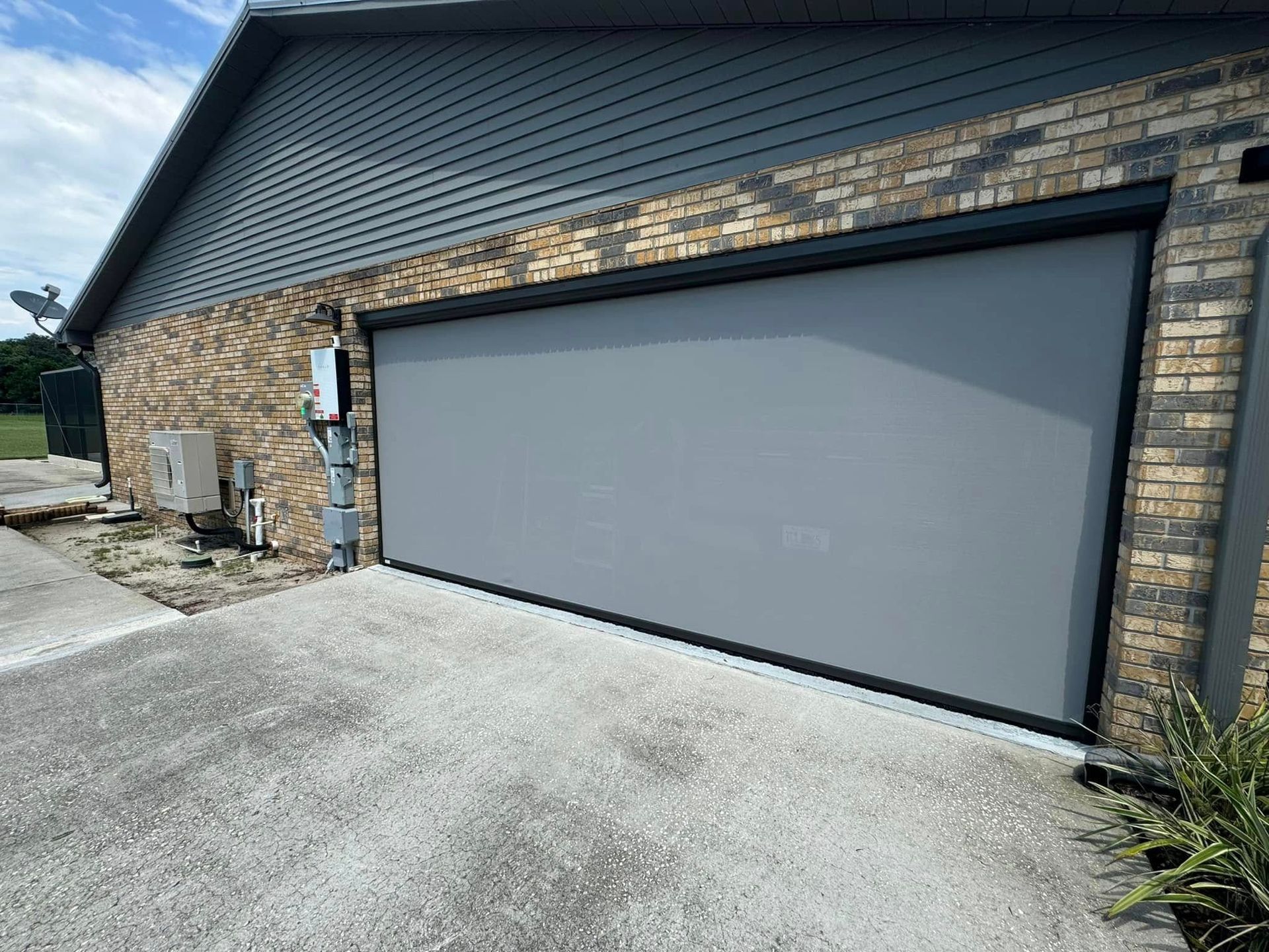 Modern house exterior with a gray garage door, brick siding, and a concrete driveway.
