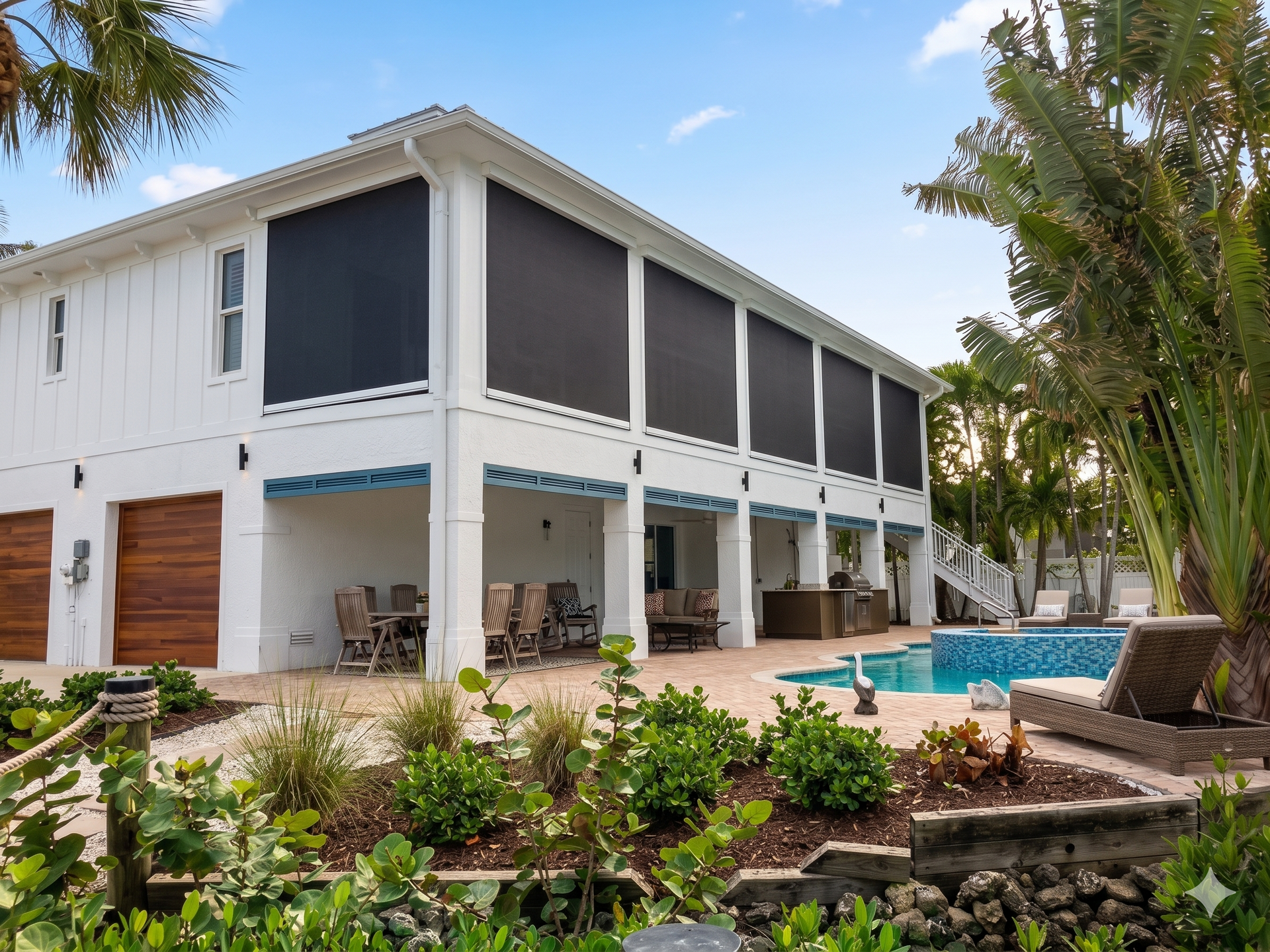Two-story white house with screened porches beside a pool and tropical landscaping