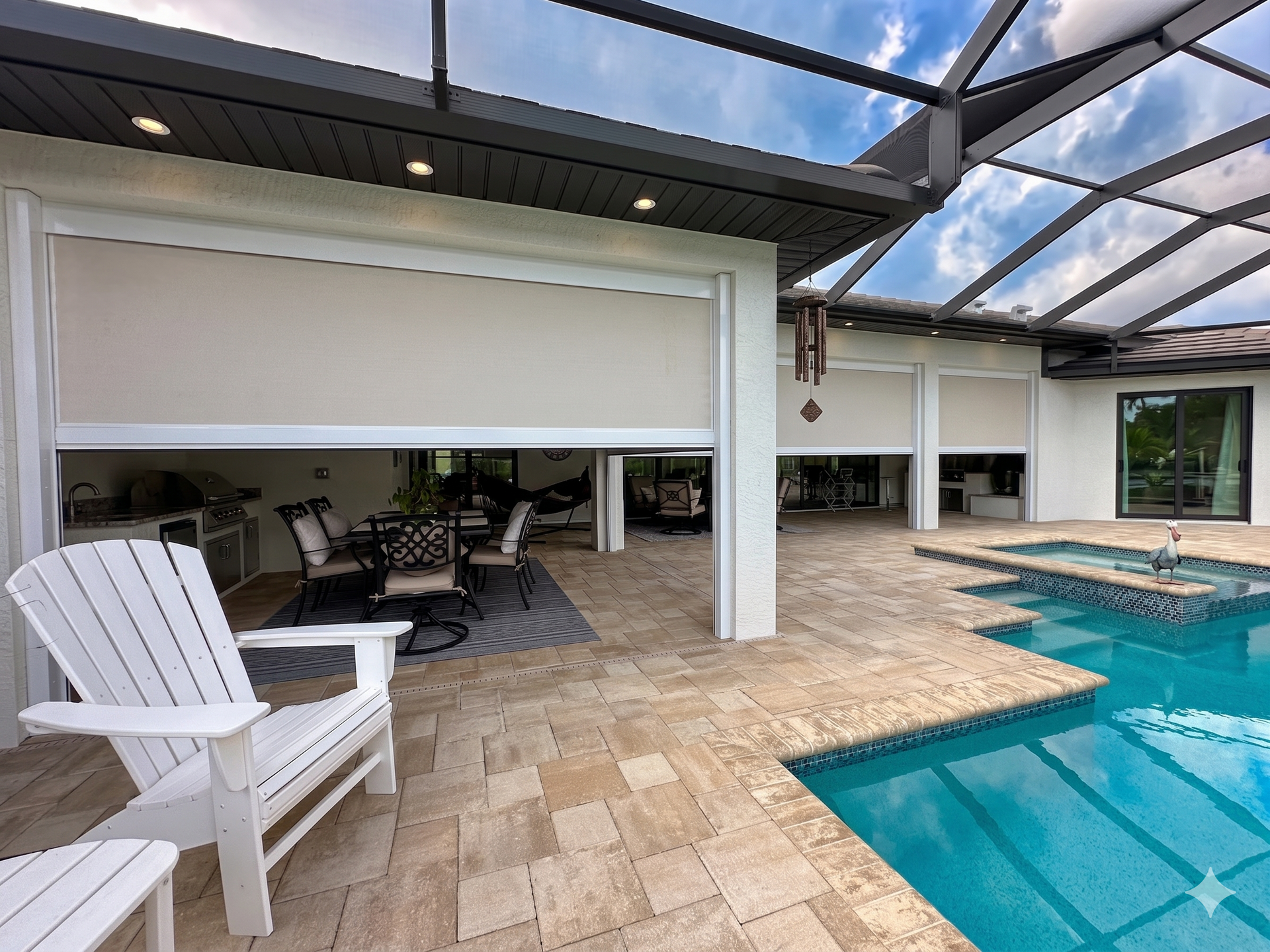 Poolside patio with white chairs, covered seating area, and turquoise swimming pool under a screened roof