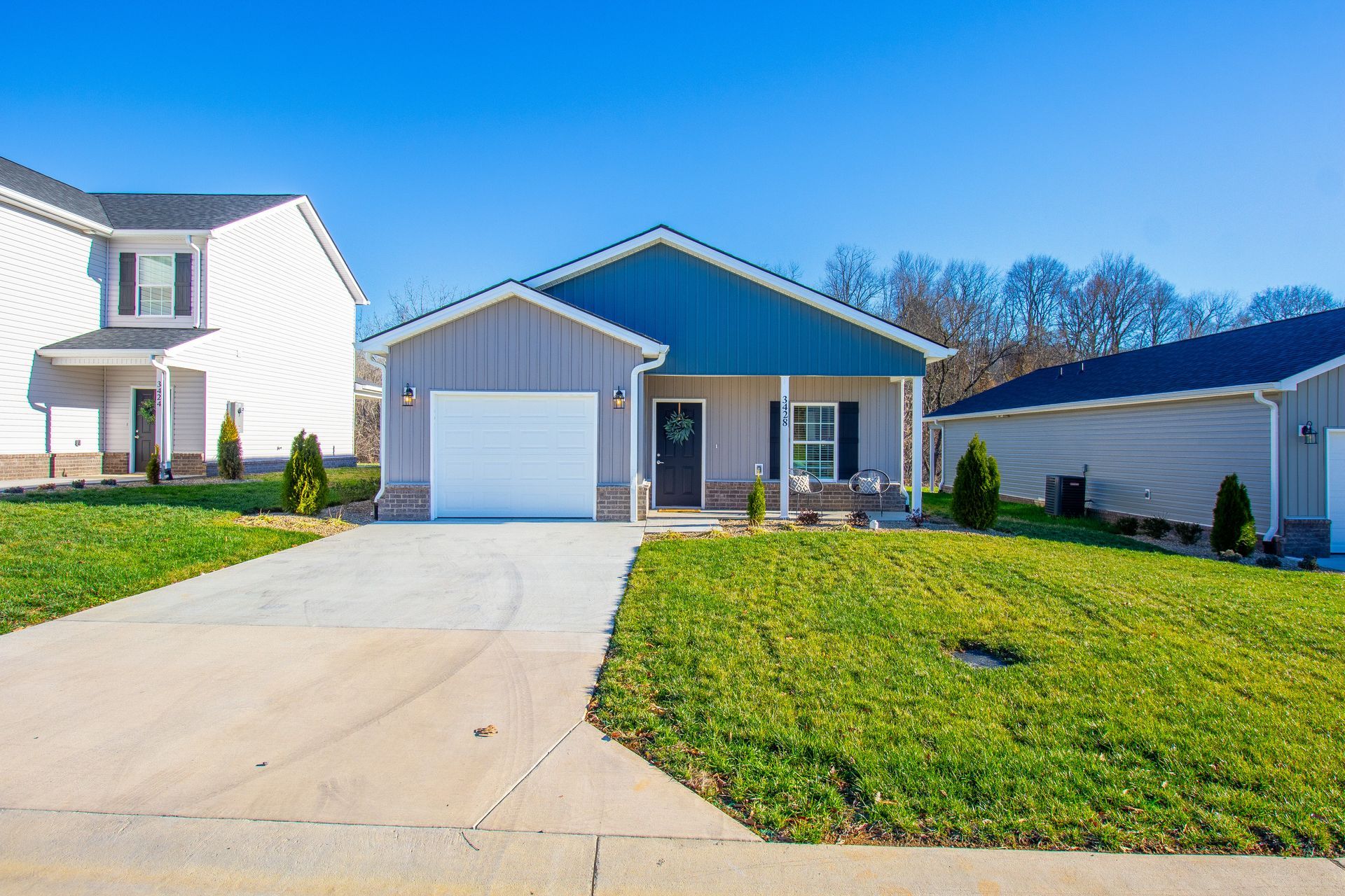 Suburban house with blue siding, white garage, and green lawn beside a driveway