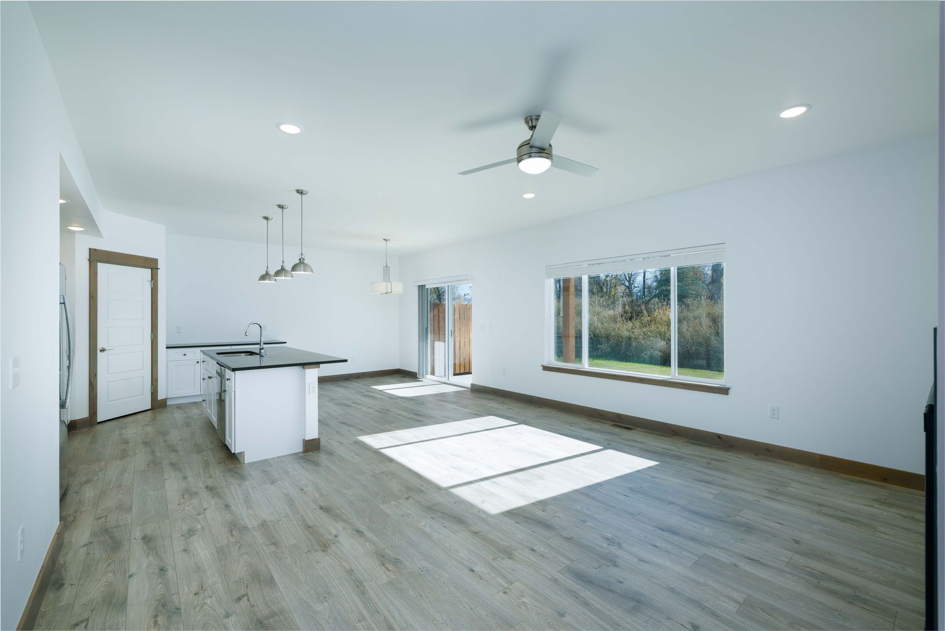 An empty living room with hardwood floors and a ceiling fan.