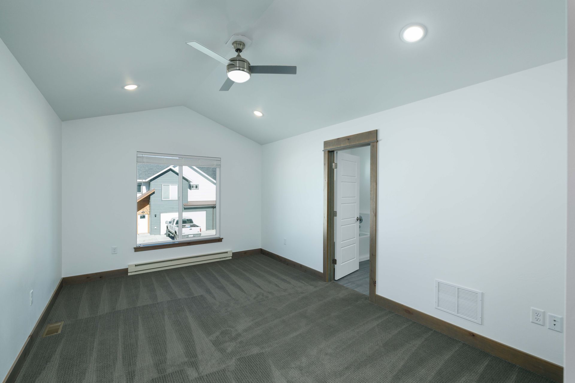 An empty room with a ceiling fan and a window.