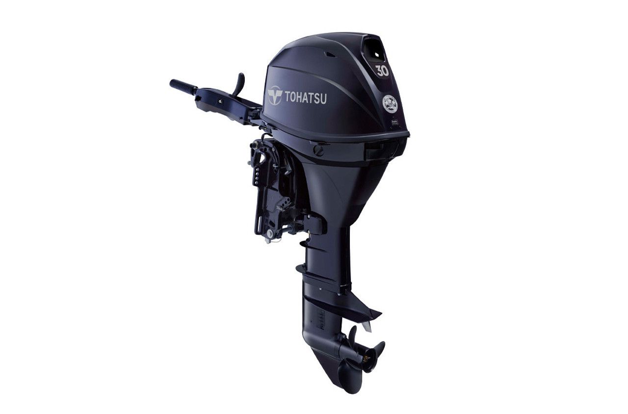 A black outboard motor is sitting on a white surface.