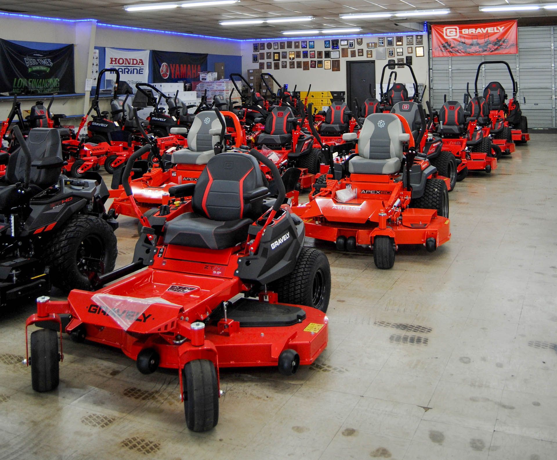 A row of red lawn mowers are lined up in a garage
