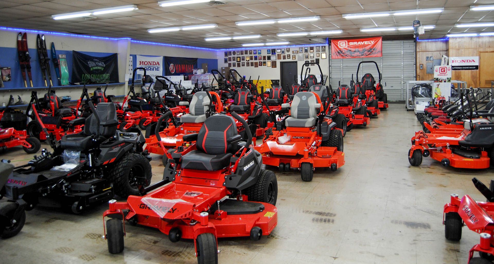 A large room filled with lots of red and black lawn mowers.
