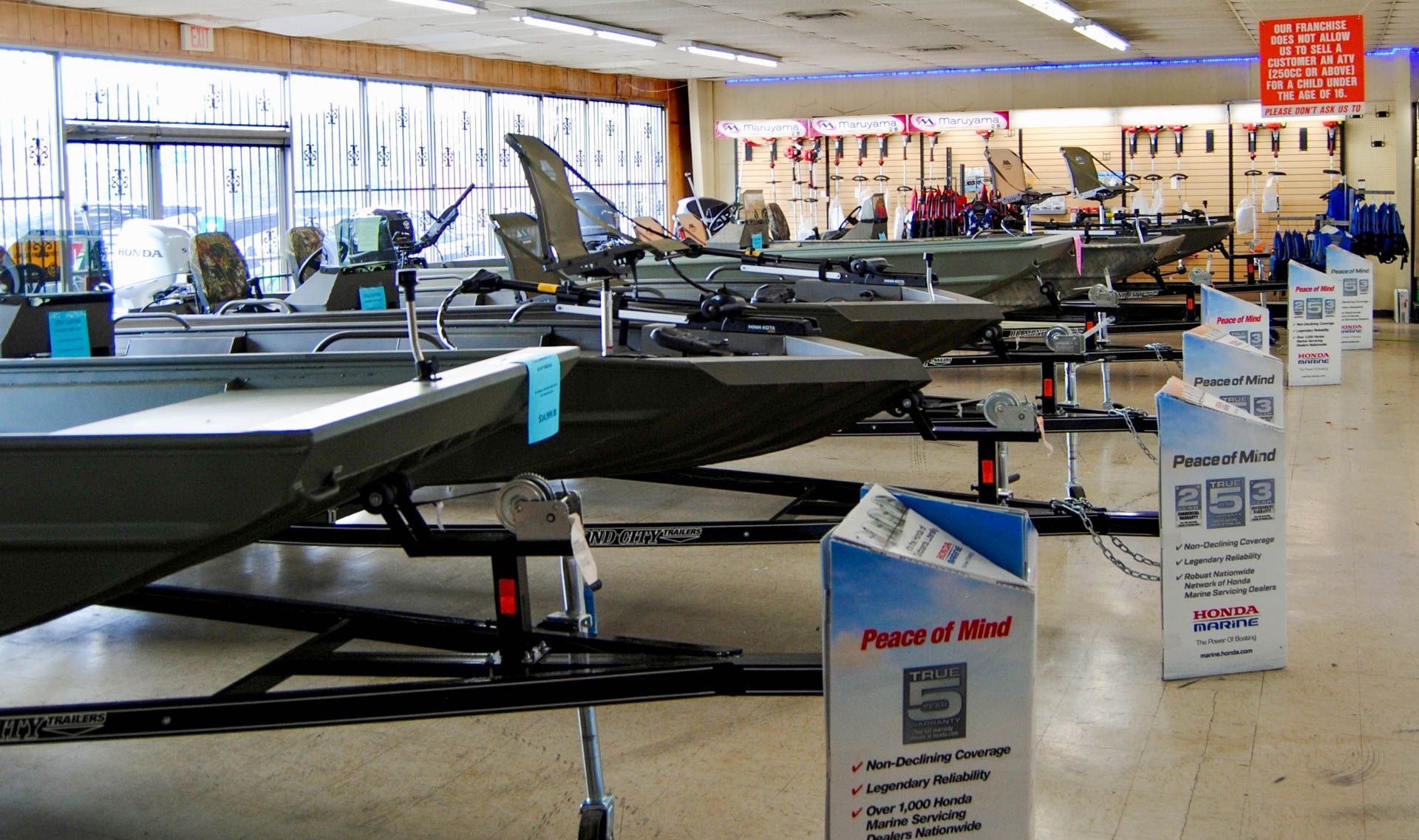 A row of boats and trailers in a store with a sign that says peace of mind
