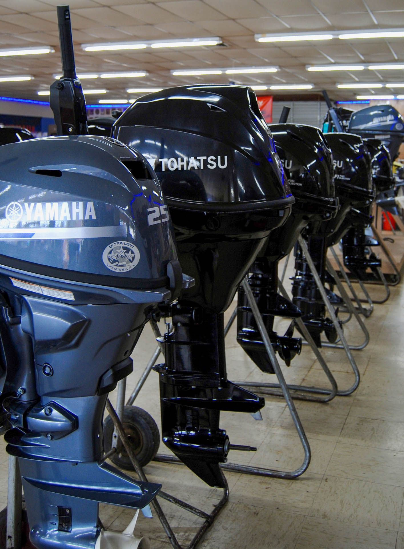 A row of yamaha outboard motors are lined up in a store