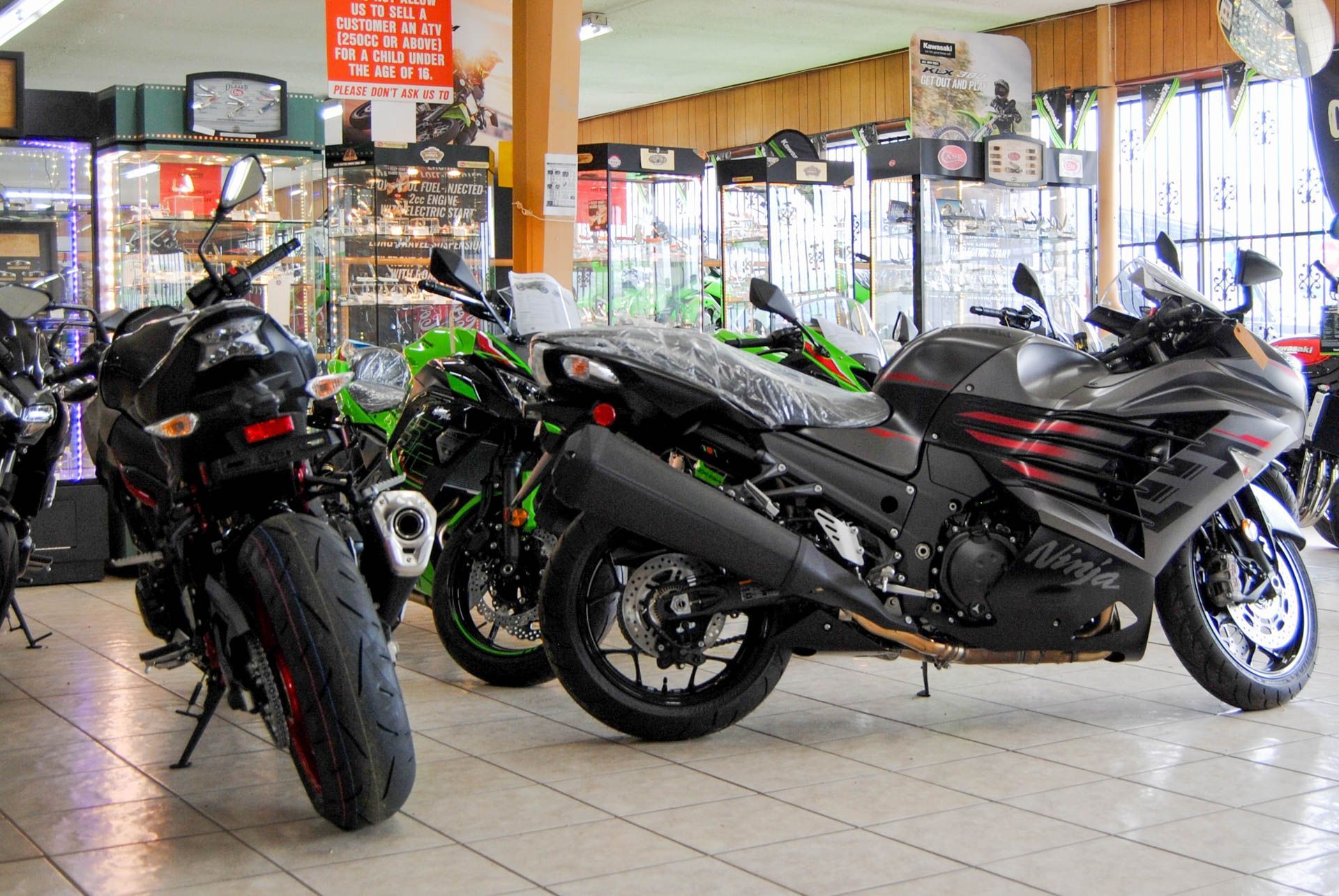 A row of motorcycles are parked in a showroom.